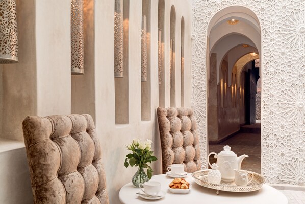A luxurious room with a tufted armchair, a table set with a teapot, cups, and a tray of pastries. - Riad Star by Marrakech Riad (Marrakech)