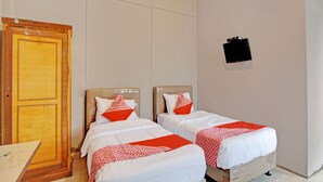 A hotel room with two beds, a wooden wardrobe, and a blackboard on the wall.