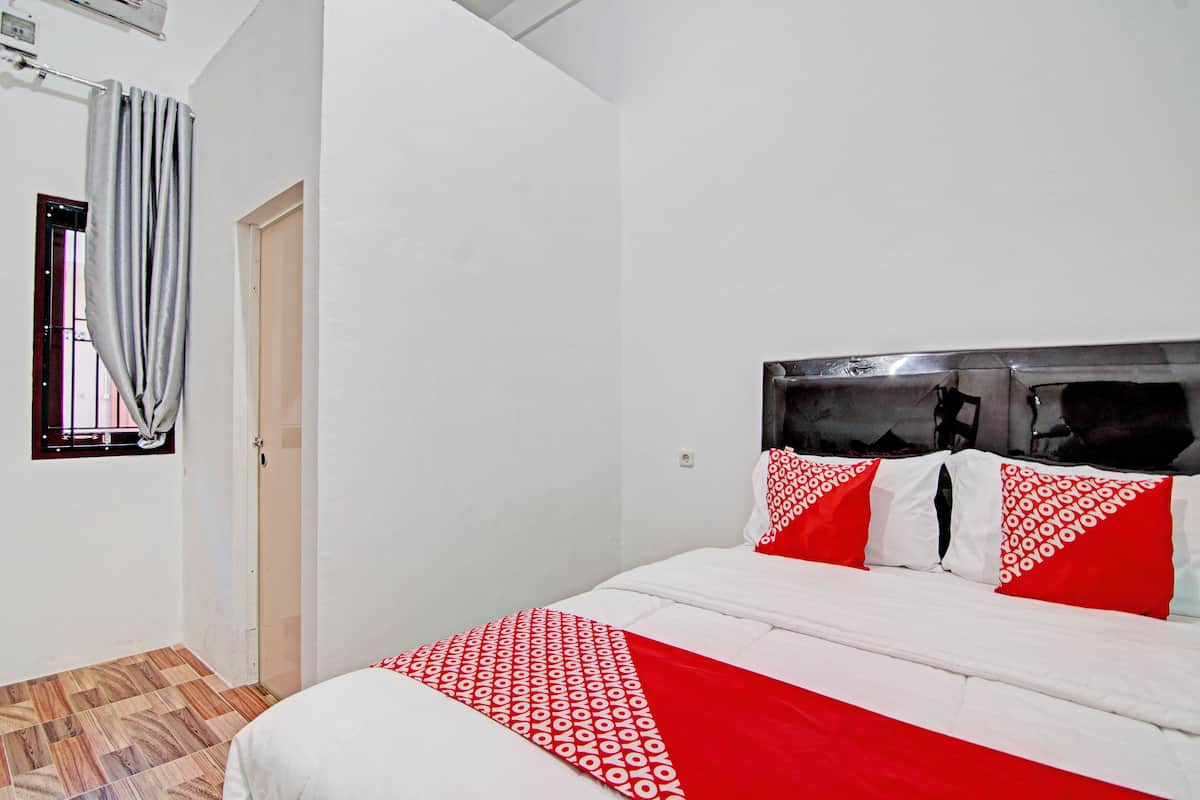 Een slaapkamer met een bed, een raam met gordijnen en een deur.