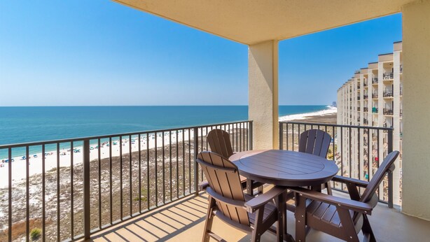 Un balcone con tavolo e sedie, vista su una spiaggia e l'oceano.