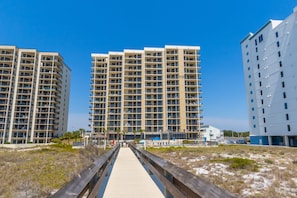 A multi-story residential building with a central walkway leading to the entrance. - Beachfront Getaway at Phoenix 8, 1202 (Orange Beach)