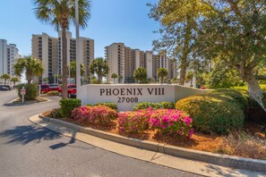 A sign for 'PHOENIX VIII 27008' with a landscaped area featuring bushes and a tree. - Beachfront Getaway at Phoenix 8, 1202 (Orange Beach)