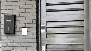 A modern gray door with a keypad lock, a small mailbox, and a number plate indicating the address as 5. - Agua Azul by tuhost (Guadalupe)