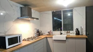 A modern kitchen with a built-in microwave, gas stove, and a window above the sink. - Agua Azul by tuhost (Guadalupe)