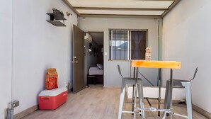 A small room with a wooden floor, a red cooler, a metal table, and a window with bars. - Agua Azul by tuhost (Guadalupe)
