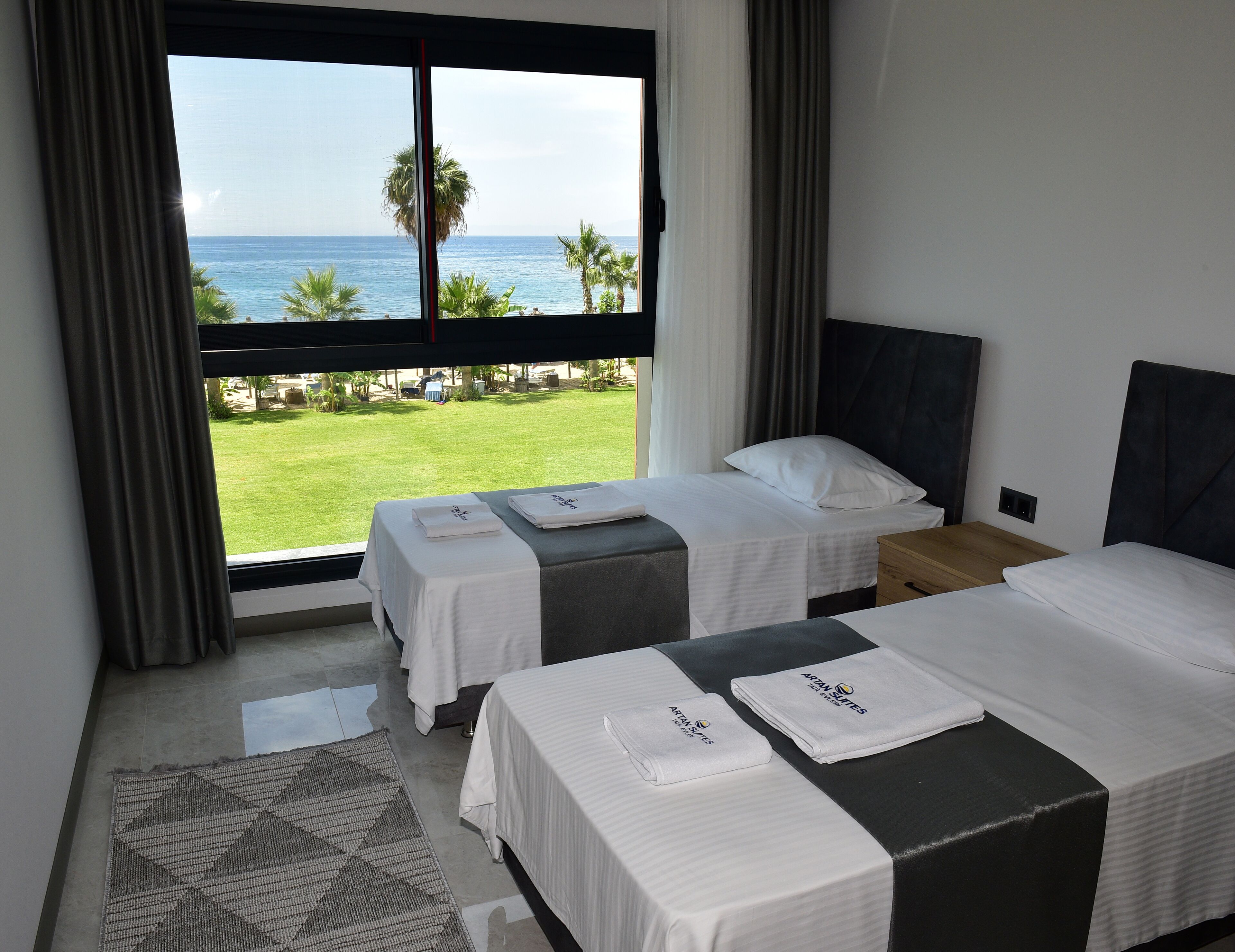 Una habitación de hotel con dos camas, vista al océano y un área verde afuera.