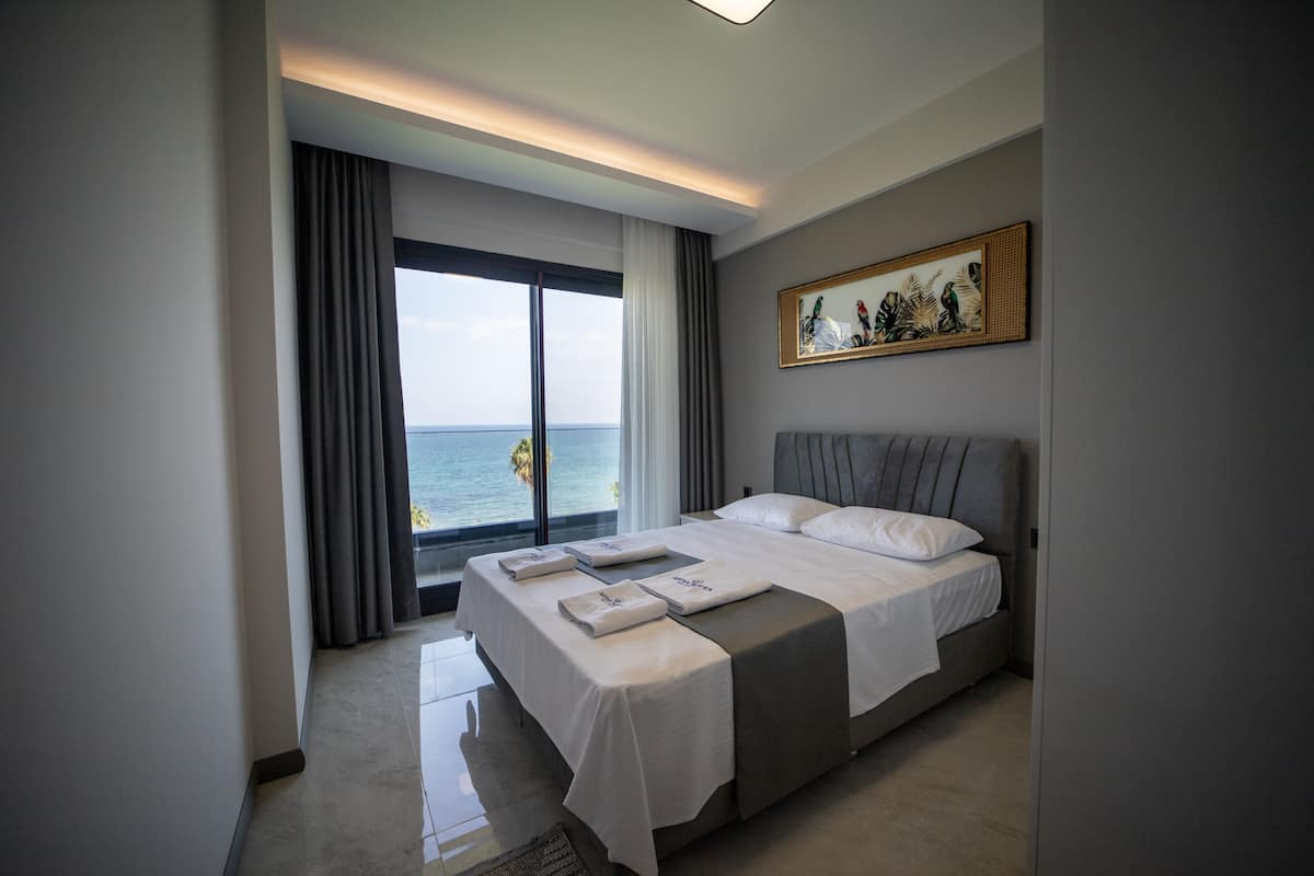 Een hotelkamer met een groot bed, uitzicht op zee en een schilderij aan de muur.