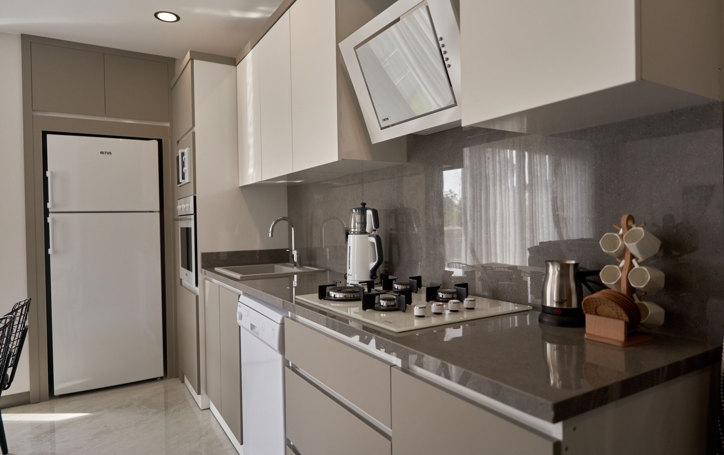 Una cocina moderna con horno empotrado, cafetera y hervidor sobre la encimera.