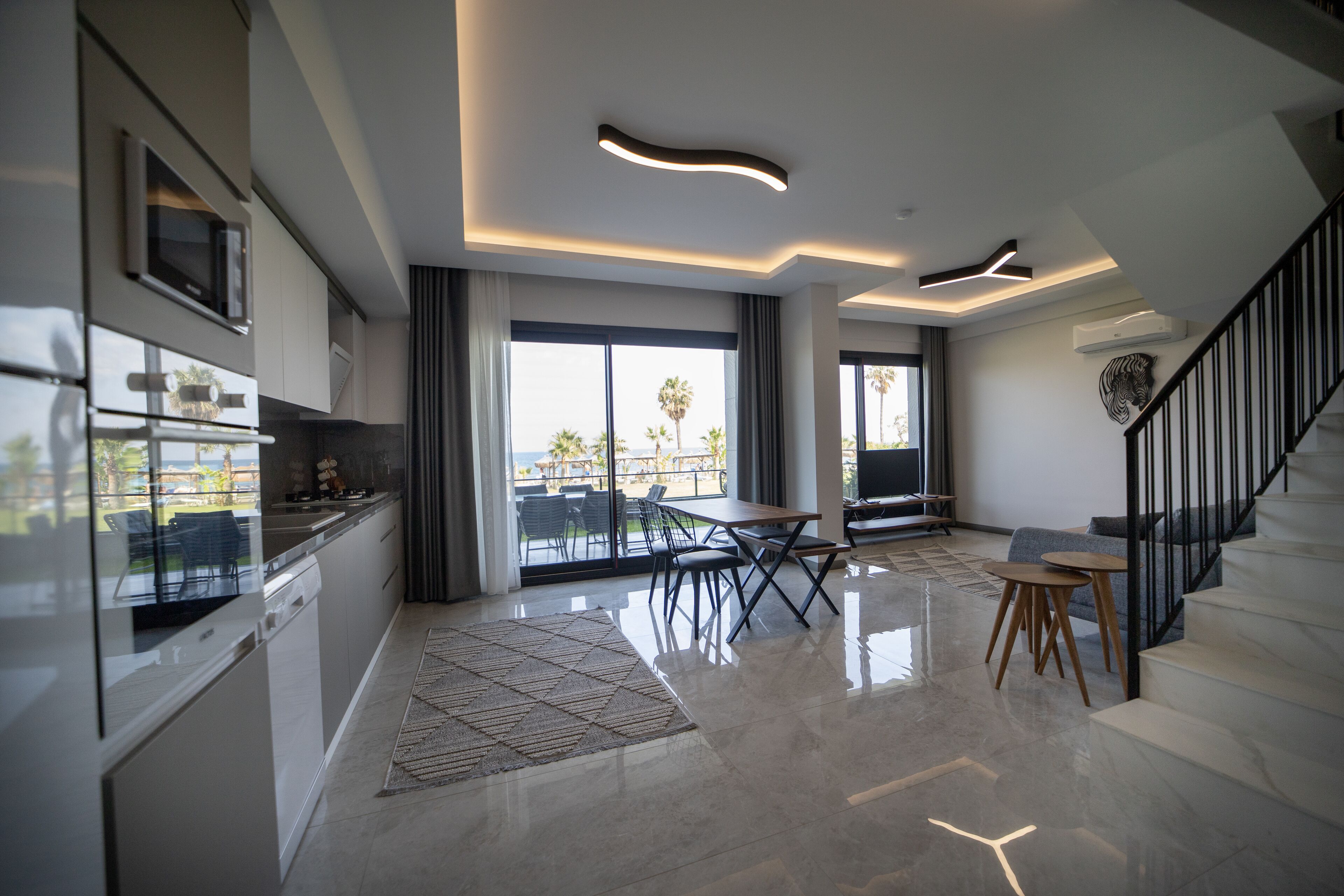 A modern kitchen with a built-in microwave, a dining area with a table and chairs, and a staircase leading to another level.