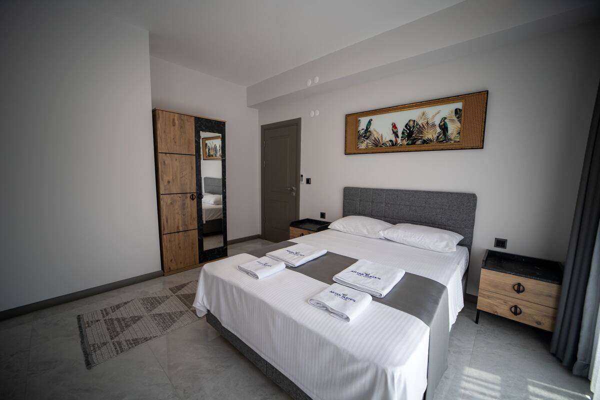 Een moderne hotelkamer met een groot bed, een houten garderobe, een nachtkastje en een schilderij aan de muur.
