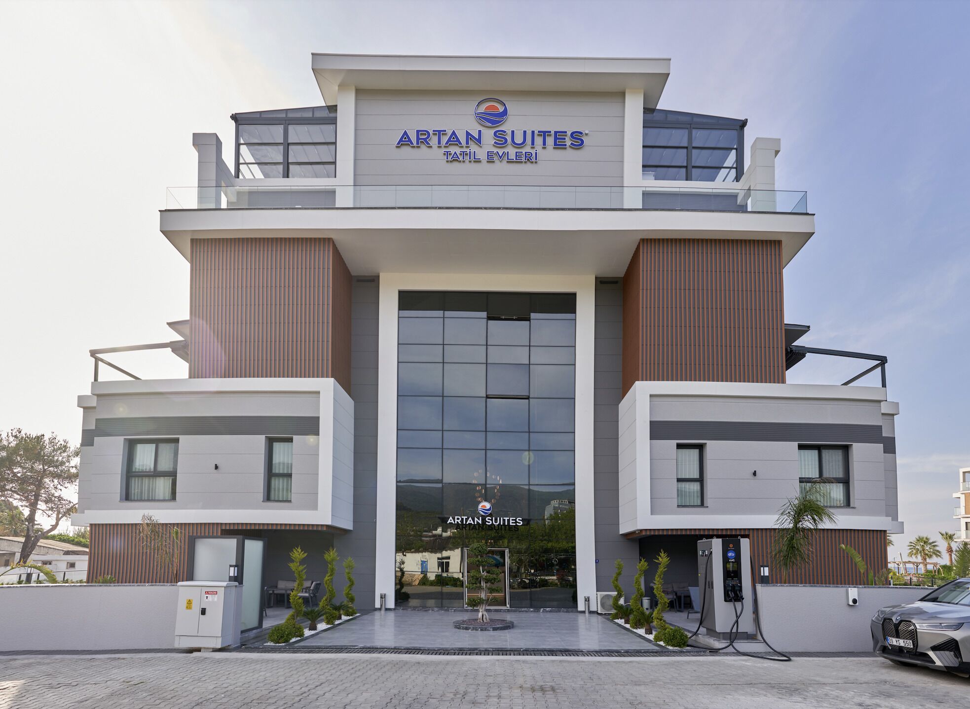A modern hotel building with a prominent entrance, large windows, and a sign reading "ARTAN SUITES".