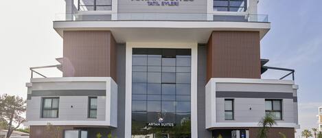 A modern hotel building with a prominent entrance, large windows, and a sign reading "ARTAN SUITES".