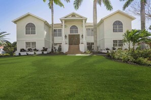A large, two-story house with a symmetrical facade, a central entrance with a door, and a well-maintained lawn. - Luxury 6BR Retreat with Beach Access (Sarasota)