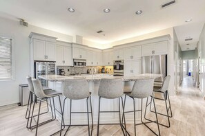 A modern kitchen with a central island, bar stools, and built-in appliances. - Luxury 6BR Retreat with Beach Access (Sarasota)