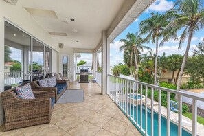 A covered outdoor area with a pool, a grill, and a wicker sofa with cushions. - Luxury 6BR Retreat with Beach Access (Sarasota)