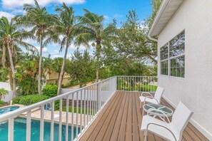 Une terrasse en bois avec des rampes blanches, une piscine et des chaises longues blanches.