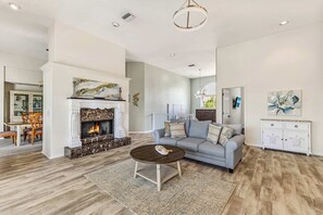 A spacious living room with a fireplace, a sofa, a coffee table, and a dining area with chairs. - Luxury 6BR Retreat with Beach Access (Sarasota)