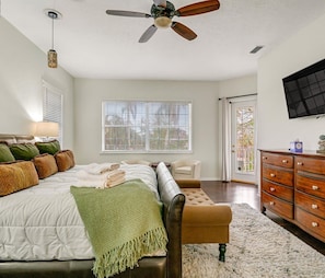 A bedroom with a bed, a sofa, a wooden dresser, a ceiling fan, and a window with blinds. - Luxury 6BR Retreat with Beach Access (Sarasota)