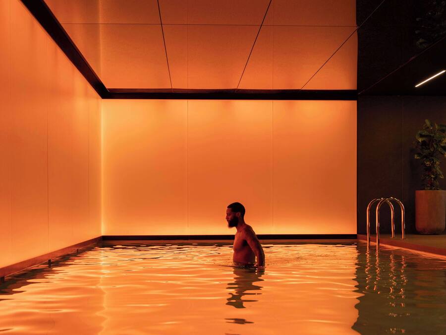 A man in a swimming pool with warm lighting and a plant in the corner.