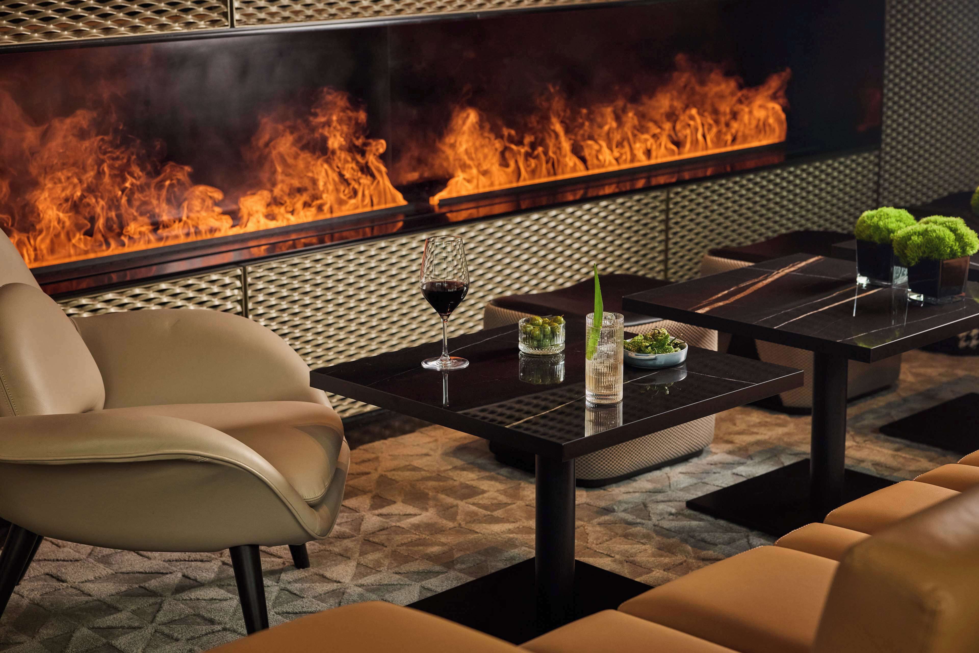A modern lounge area with a leather sofa, a black coffee table, and a glass of wine.