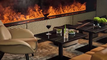 A modern lounge area with a leather sofa, a black coffee table, and a glass of wine.