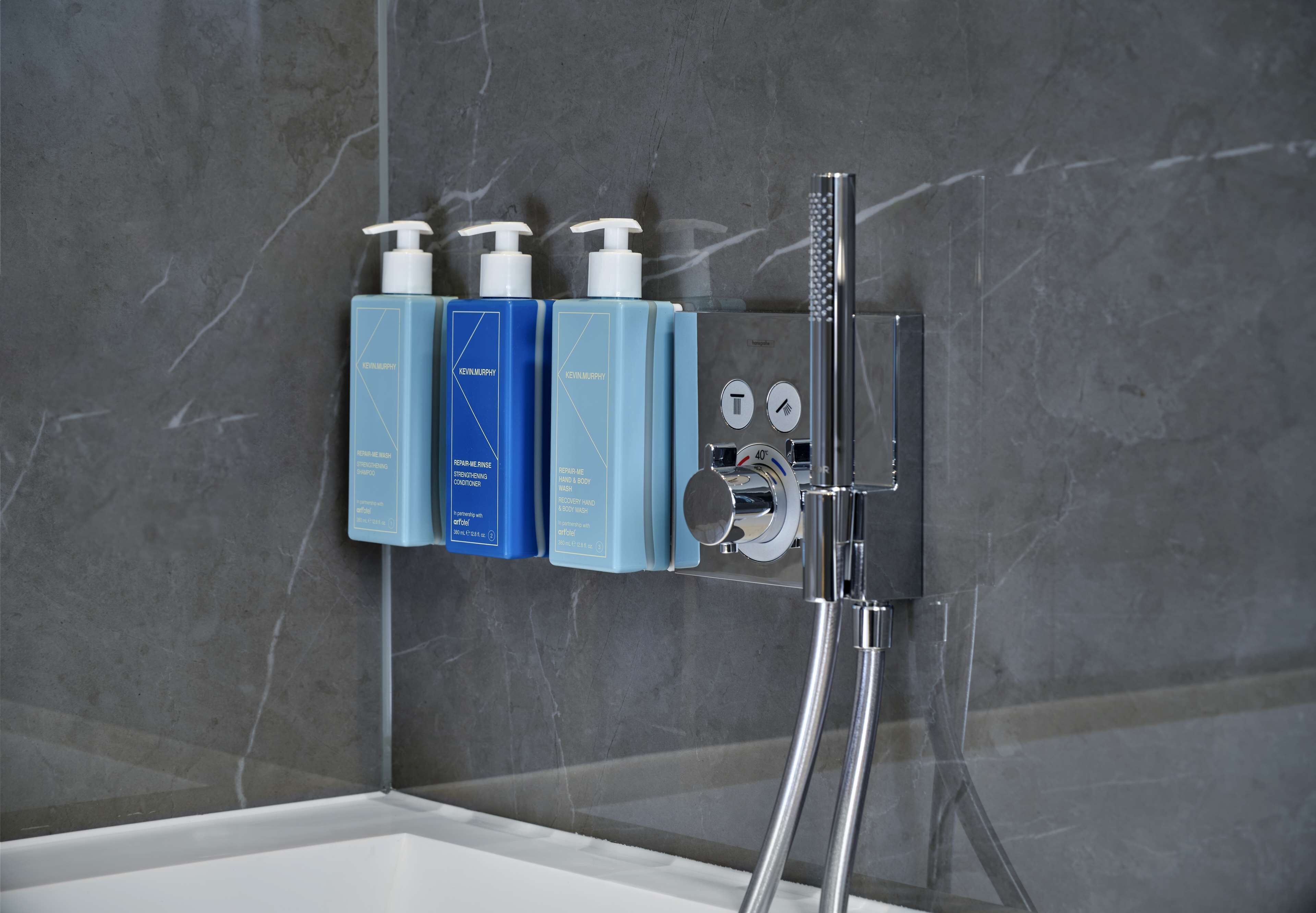 A bathroom with a modern shower system, including a handheld showerhead and control knobs.