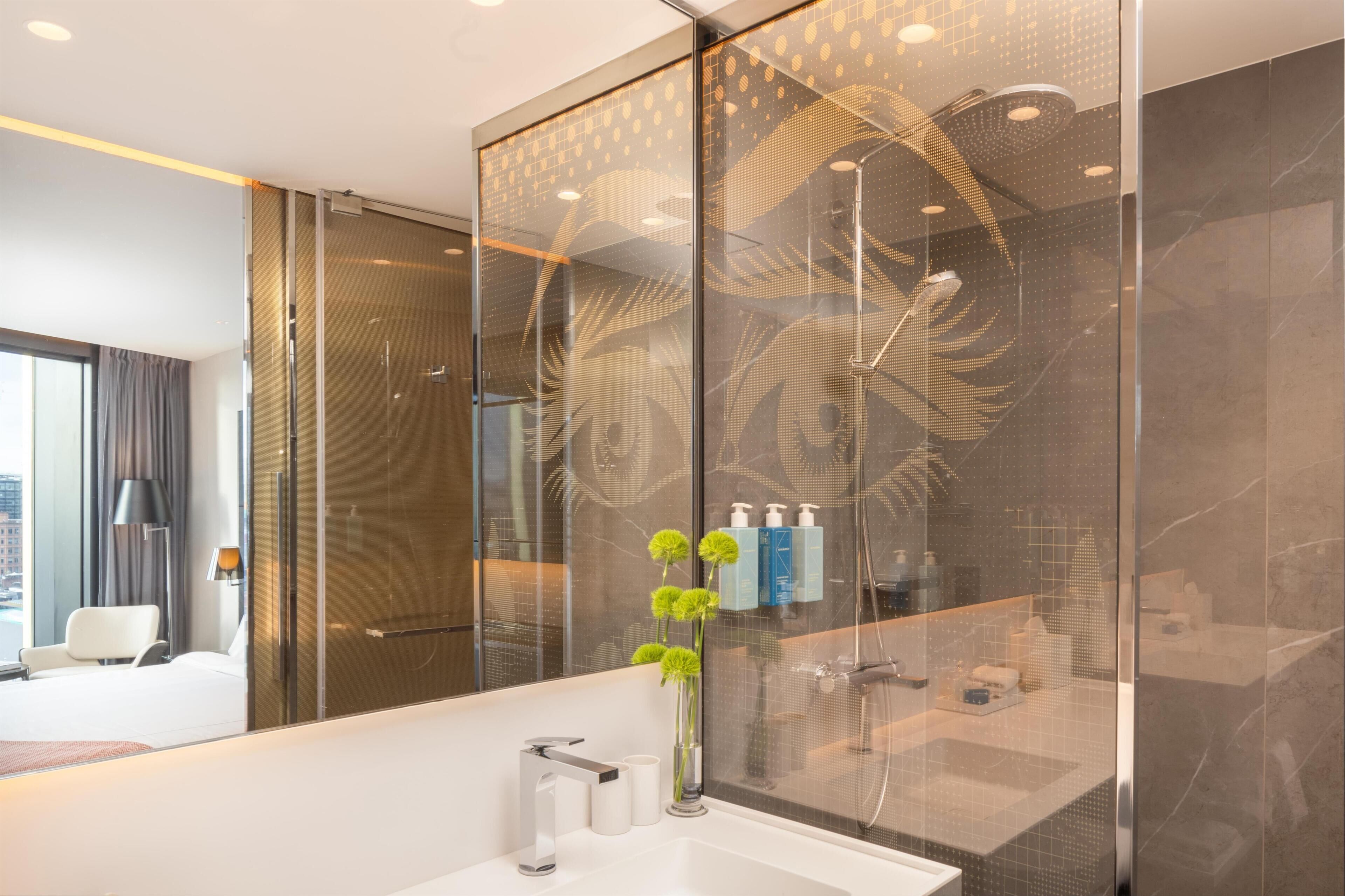 A modern bathroom with a large mirror, a white sink, and a shower area.