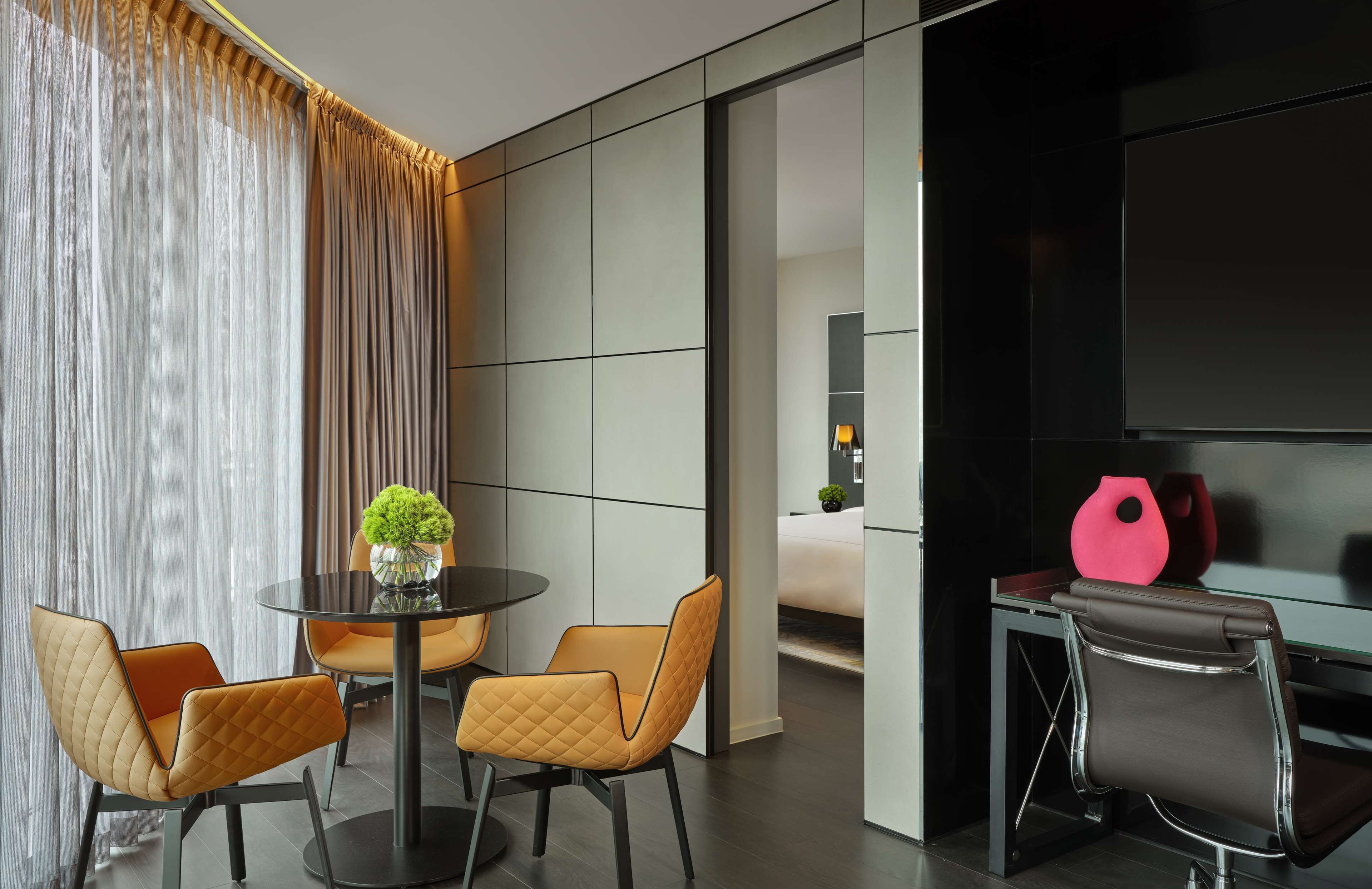 Quarto de hotel moderno com área de refeições, uma cama e uma televisão.