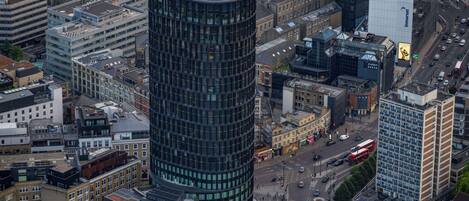 Un immeuble de grande hauteur doté d’une façade moderne en verre, entouré d’autres bâtiments dans un environnement urbain.