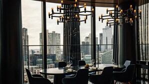 A modern dining area with a panoramic city view, large windows, and contemporary lighting fixtures. - art'otel London Hoxton (London)
