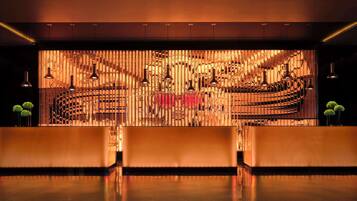 A reception area with a modern design, featuring a central counter and multiple pendant lights.