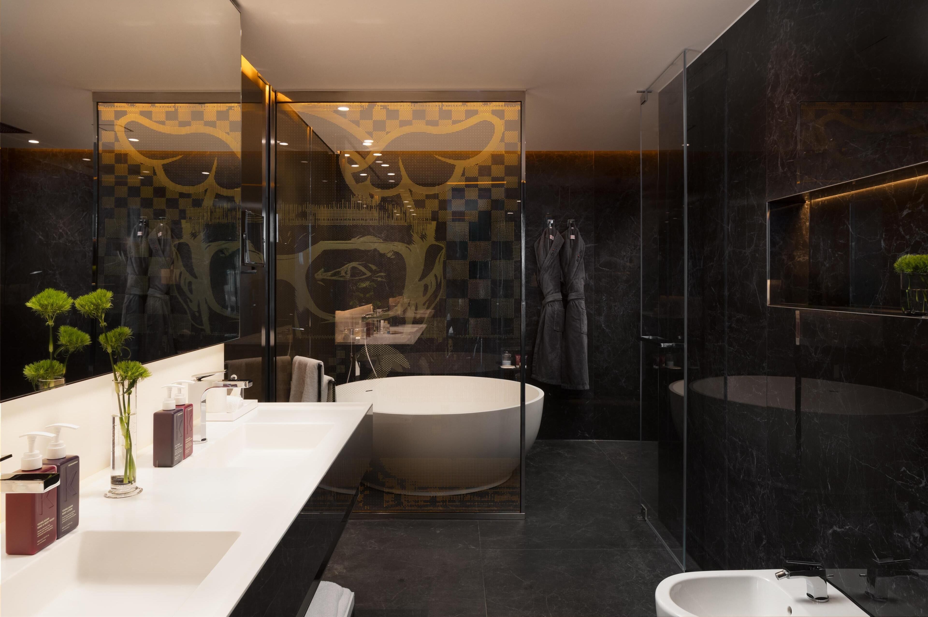 A modern bathroom with a large bathtub, a separate sink, and a glass-enclosed shower area.