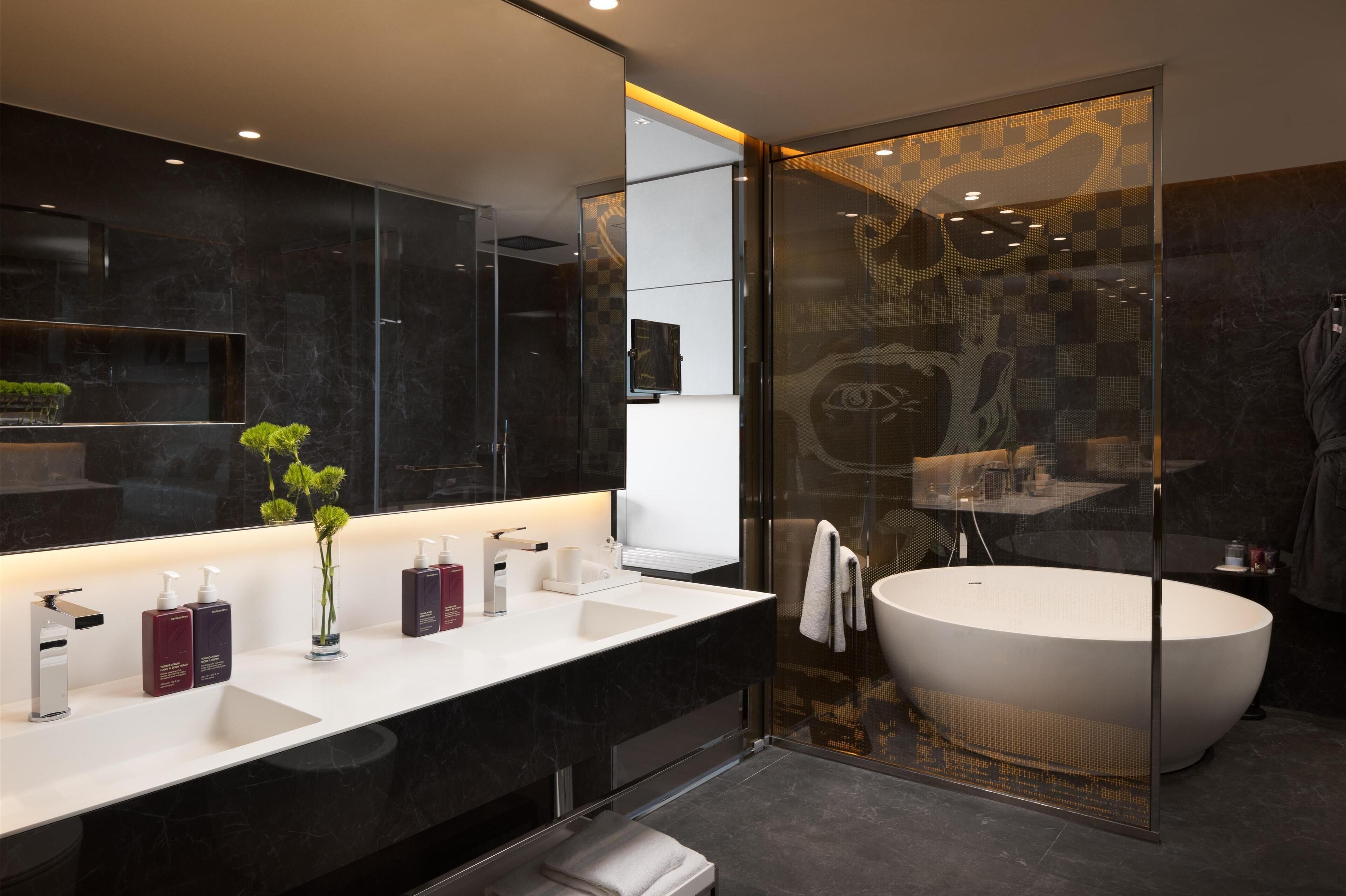 Une salle de bain moderne avec un grand miroir, un lavabo blanc et une baignoire sur pieds.