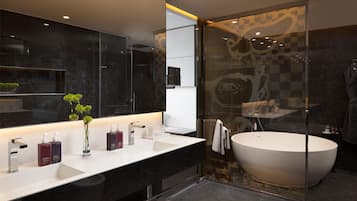 Une salle de bain moderne avec un grand miroir, un lavabo blanc et une baignoire sur pieds.