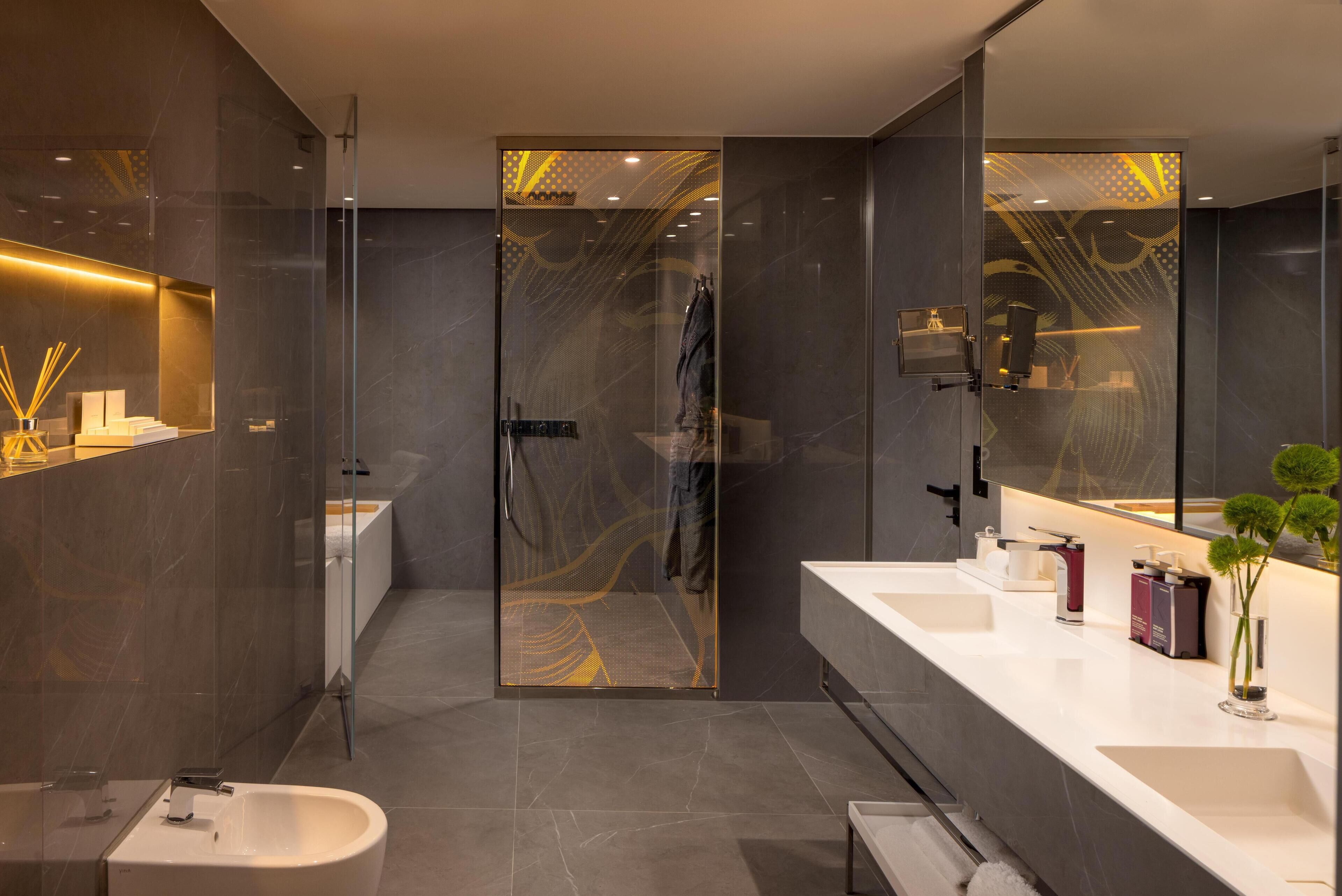 A modern bathroom with a glass shower enclosure, a white sink, and a large mirror.