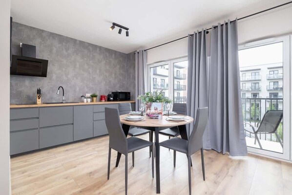 A modern kitchen with grey cabinets, a wooden countertop, and a dining area with a round table and chairs.
