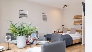 A modern hotel room with a dining area, a bed, and two framed pictures on the wall.