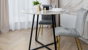 Een moderne eethoek met een ronde tafel, een stoel, een hanglamp en een radiator.