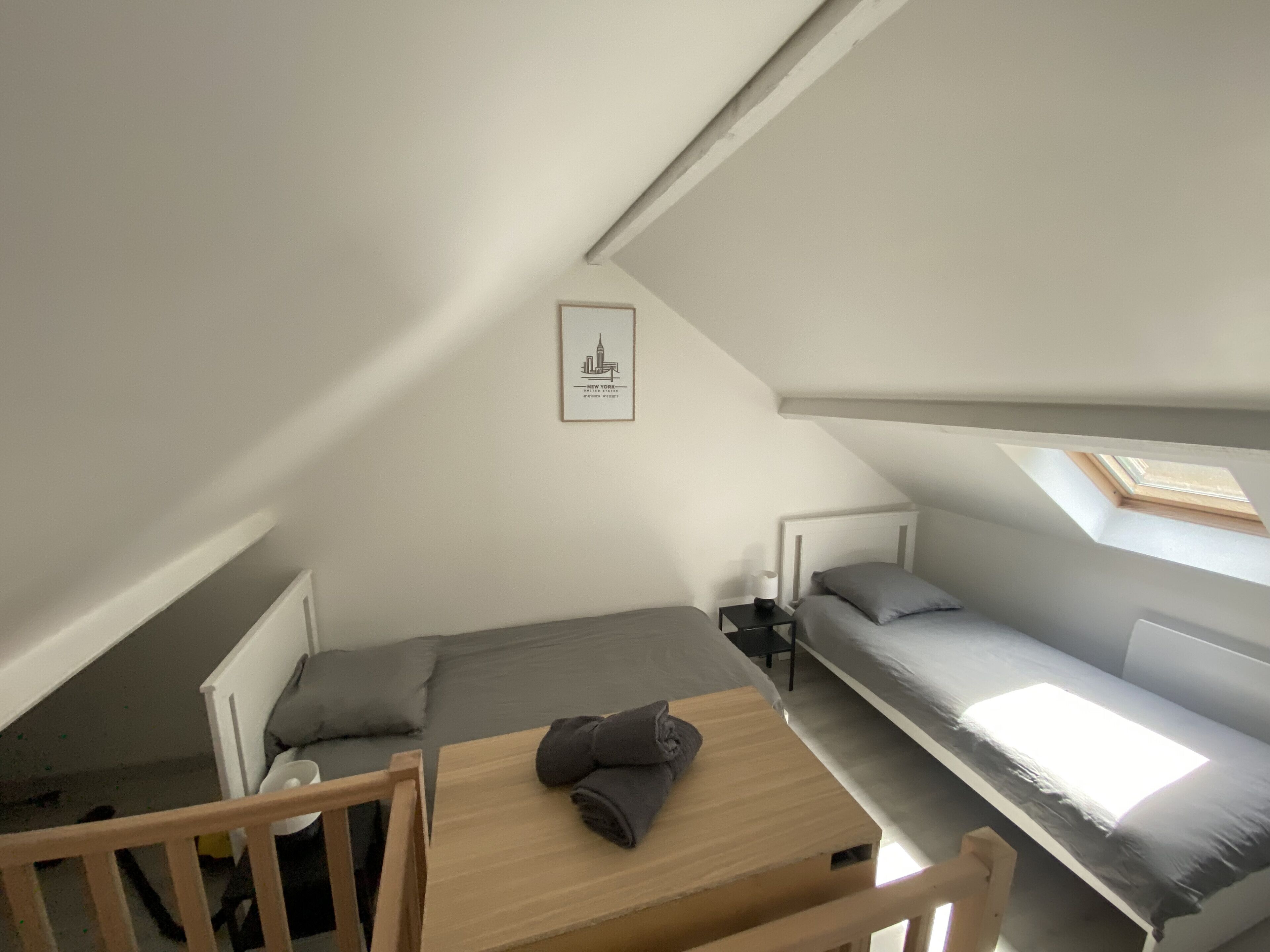 A compact room with a bunk bed, a small table with a towel, and a framed picture on the wall.