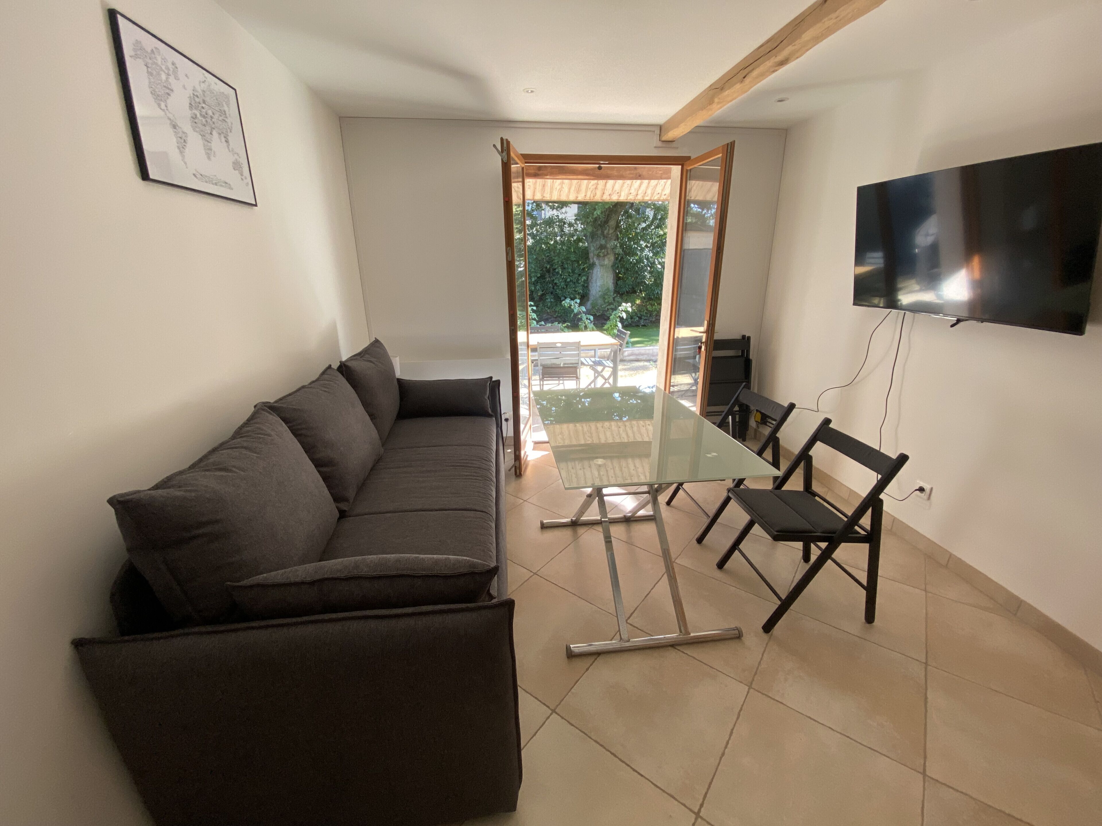 Un soggiorno moderno con un divano componibile, un tavolino con piano in vetro e una TV a schermo piatto fissata al muro.