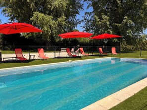 Une piscine avec des parasols rouges et des chaises longues.