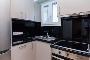 A kitchen with a black countertop, stainless steel sink, and a stove.