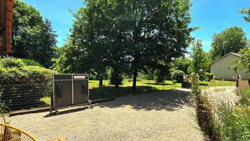 A wooden deck with a chair, a gravel area, and a large tree in the background.