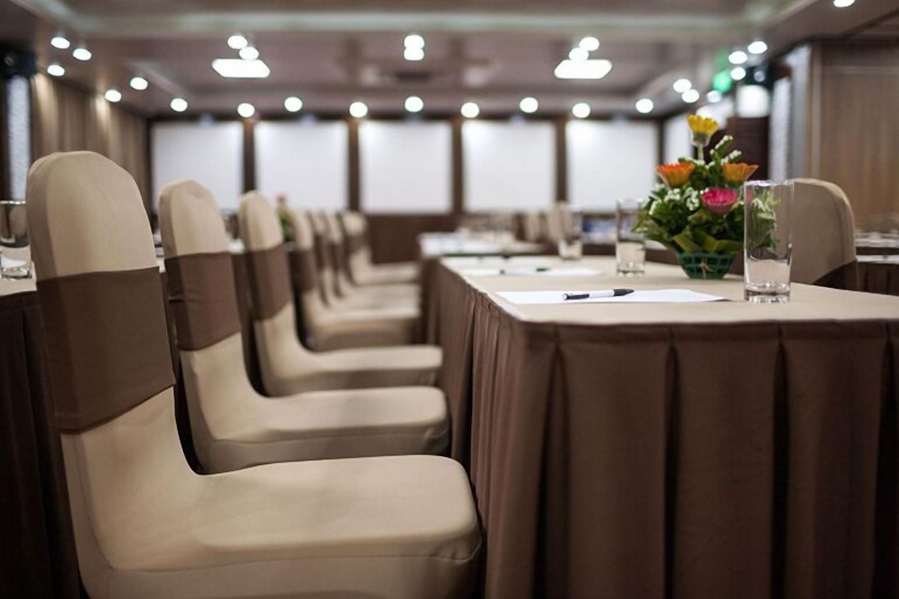 Un salón de conferencias con filas de sillas y mesas, cada una cubierta con un mantel marrón.