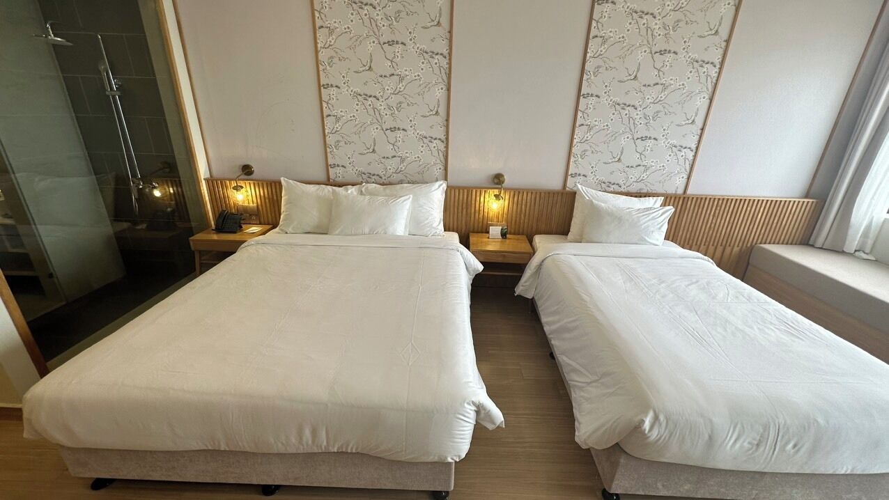 Une chambre d’hôtel avec deux lits, une douche et une tête de lit en bois.