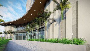 A modern building with a curved roof, large windows, and palm trees. - Seabird Hotel Thien Cam (Thiên Cầm)