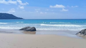 A beach with clear skies, calm waves, and rocky outcrops. - Villa Nordic Star Seaview Near Kata Beach (Muang)
