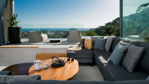 A modern living room with a large window, a sofa, a coffee table, and a view of the ocean. - Villa Nordic Star Seaview Near Kata Beach (Muang)