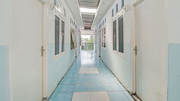 A corridor with tiled flooring and doors on both sides. - Hotel O Marvel House Syariah (Pekanbaru)