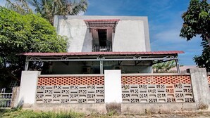 A building with a concrete facade, a red-tiled roof, and a brick-patterned wall. - Hotel O Marvel House Syariah (Pekanbaru)